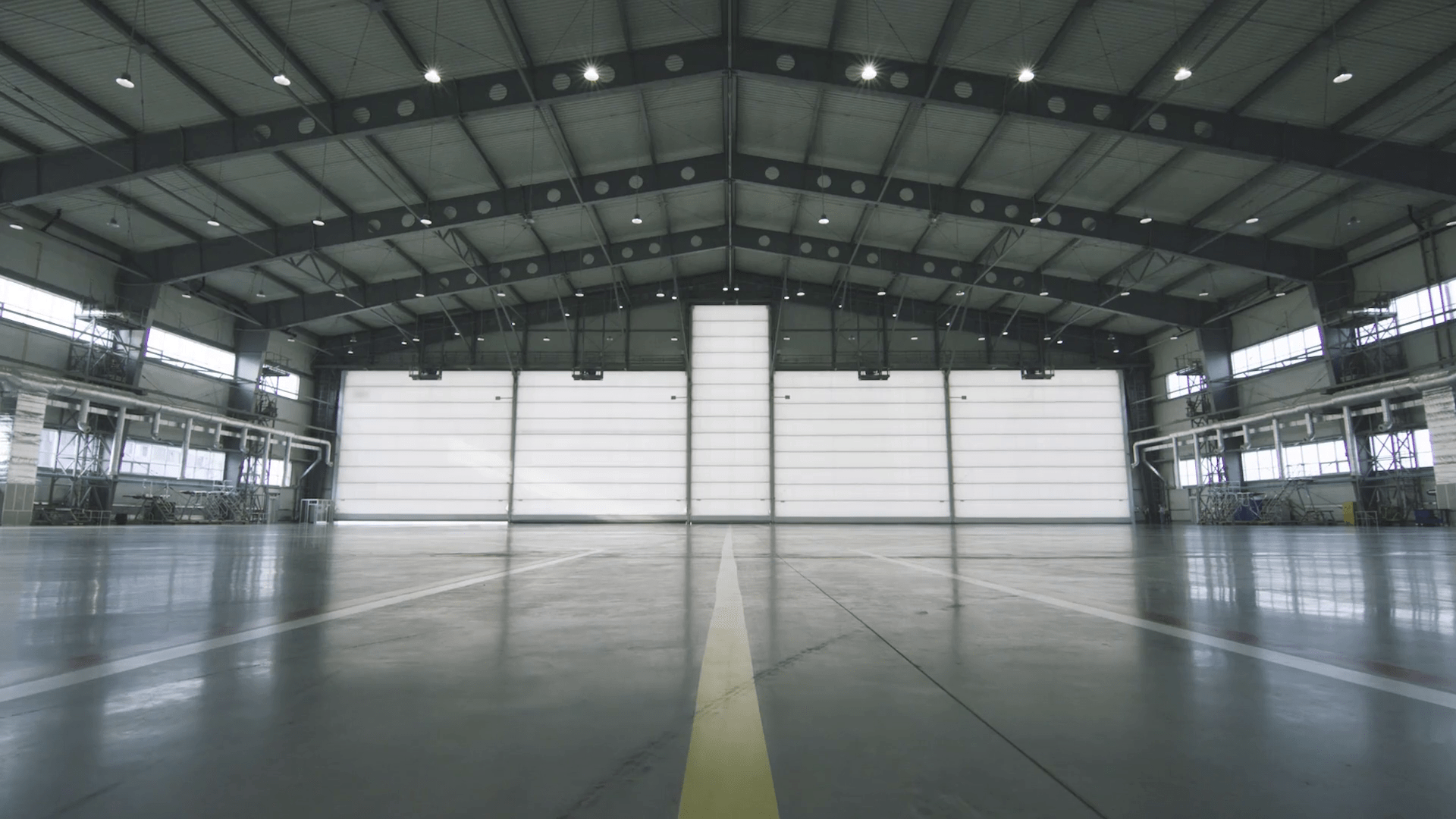 videoblocks-roller-shutter-door-and-concrete-floor-inside-factory-building-for-industrial-background-airplane-in-front-of-half-opened-door-to-hangar-the-open-door-of-the-hangar-mechanic-open